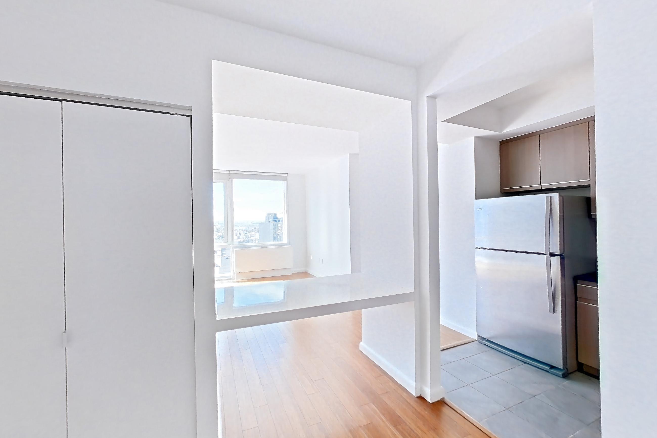 Living space with light wood-finish flooring, refrigerator, and white appliances, Apartment 24F at 66 Rockwell