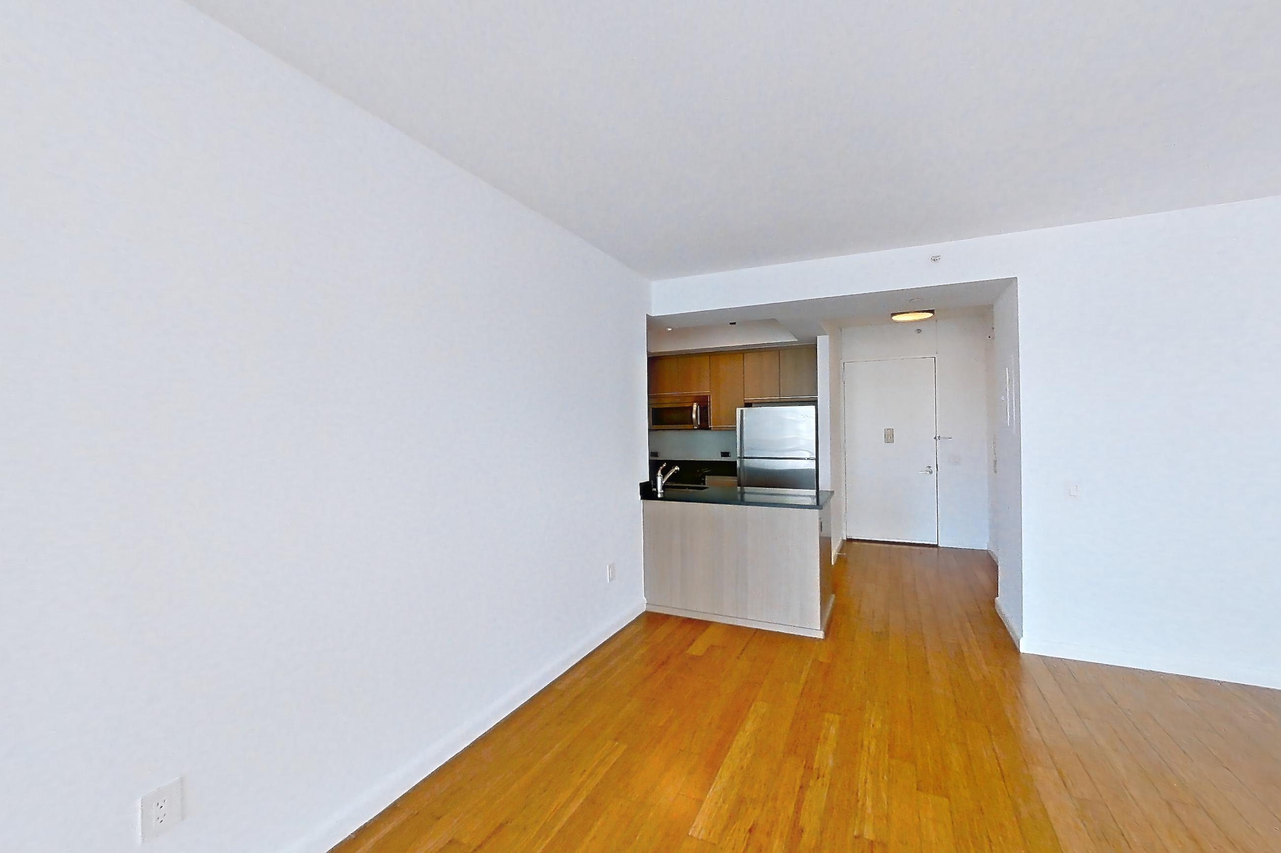 Living room with refrigerator, stainless steel appliances, and wood-finish flooring, Apartment 25A at 66 Rockwell
