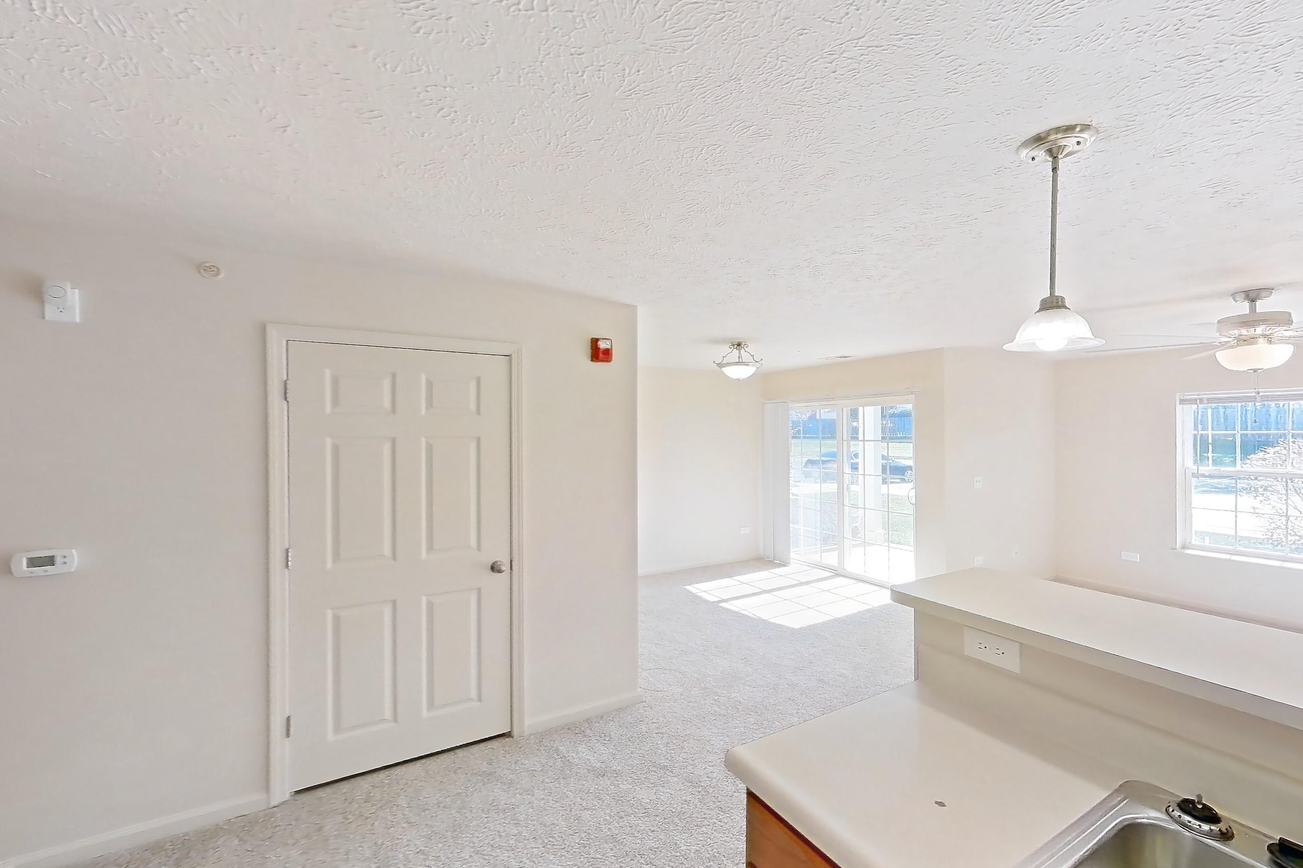 Kitchen with dishwasher, electric range, light carpet, light countertops, light wood-finish flooring, oven/range, refrigerator, and white appliances, Apartment 412 at Village Park