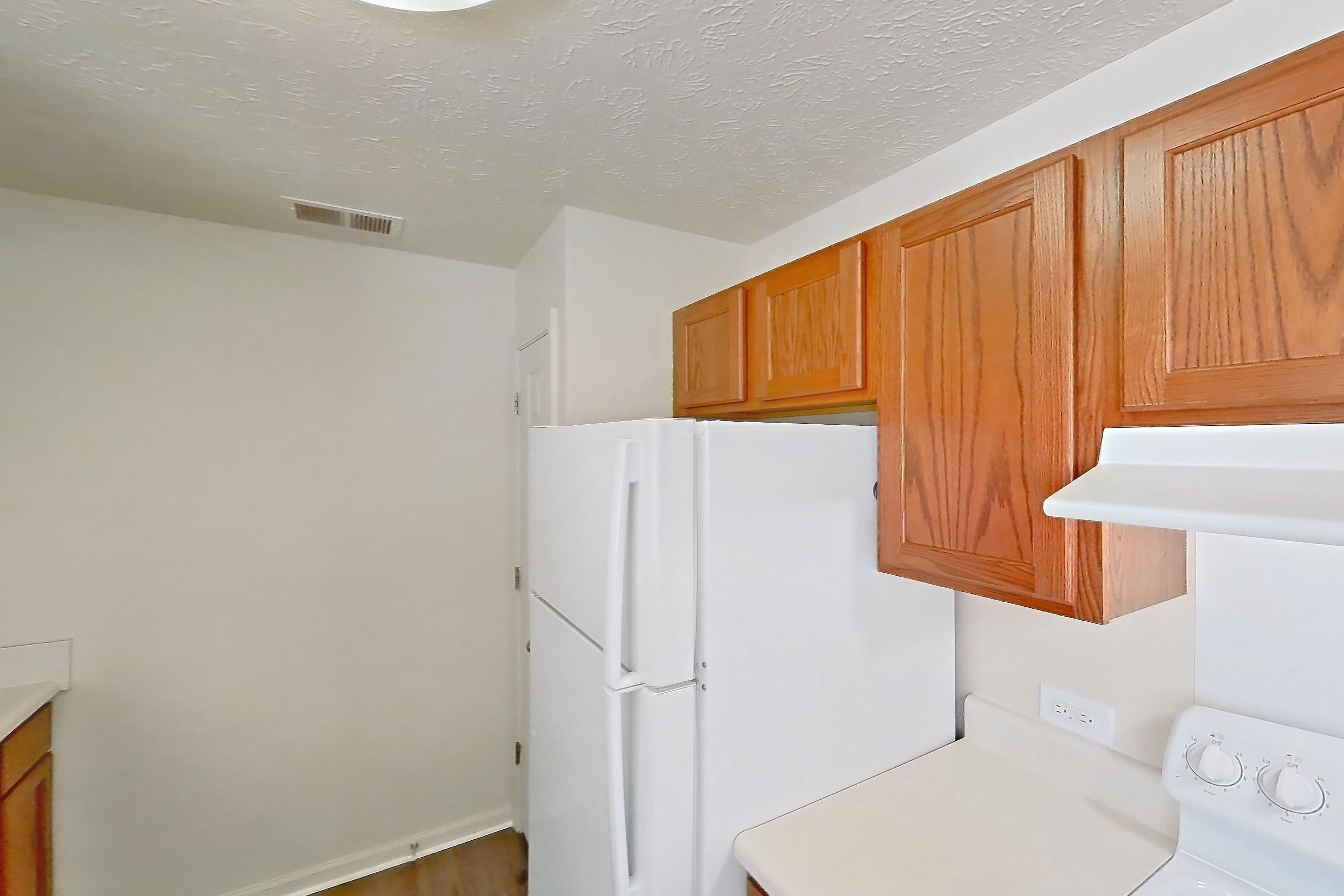 Kitchen with dishwasher, electric range, light carpet, light countertops, light wood-finish flooring, oven/range, refrigerator, and white appliances, Apartment 412 at Village Park