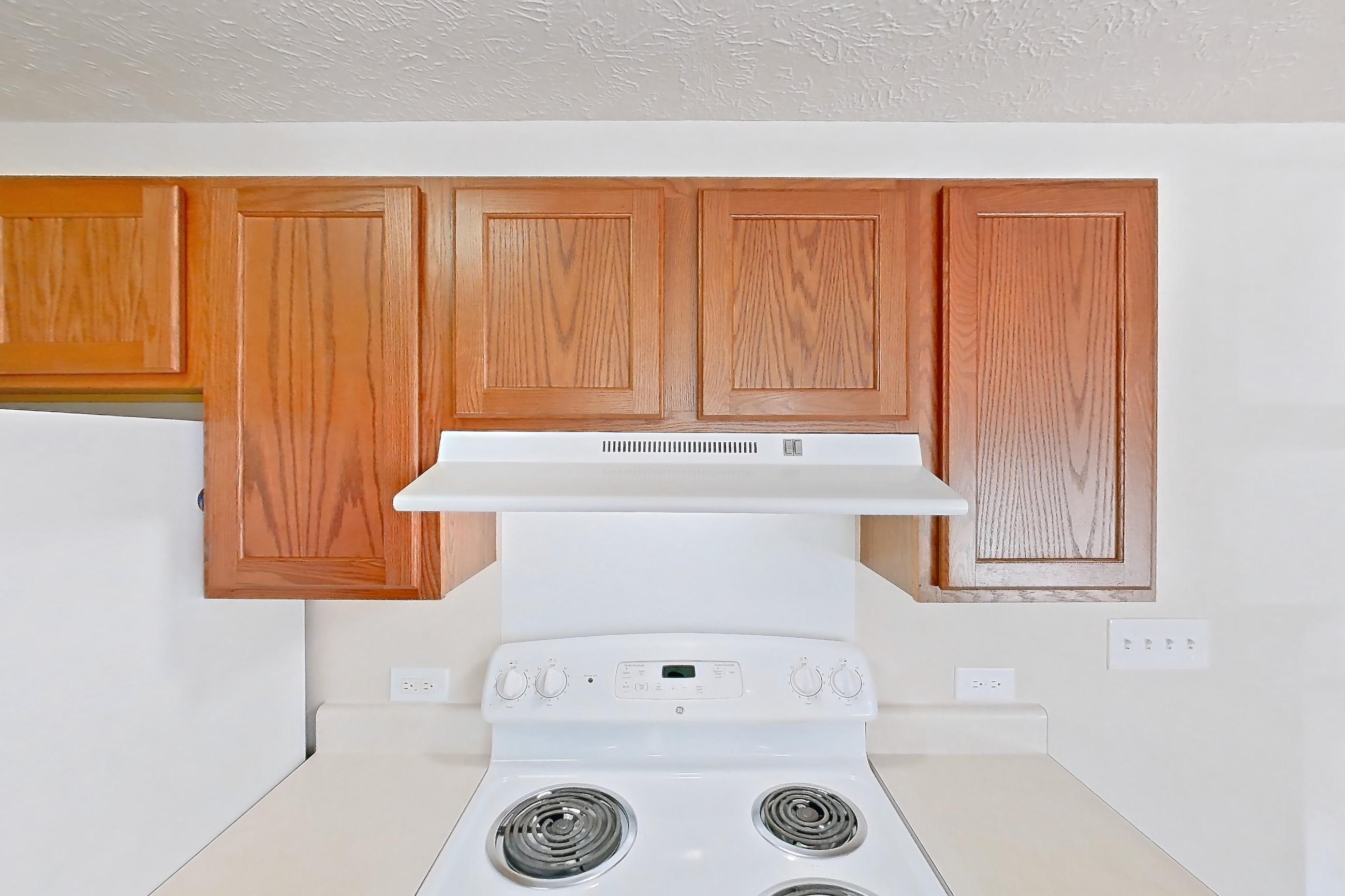 Kitchen with dishwasher, electric range, light carpet, light countertops, light wood-finish flooring, oven/range, refrigerator, and white appliances, Apartment 412 at Village Park