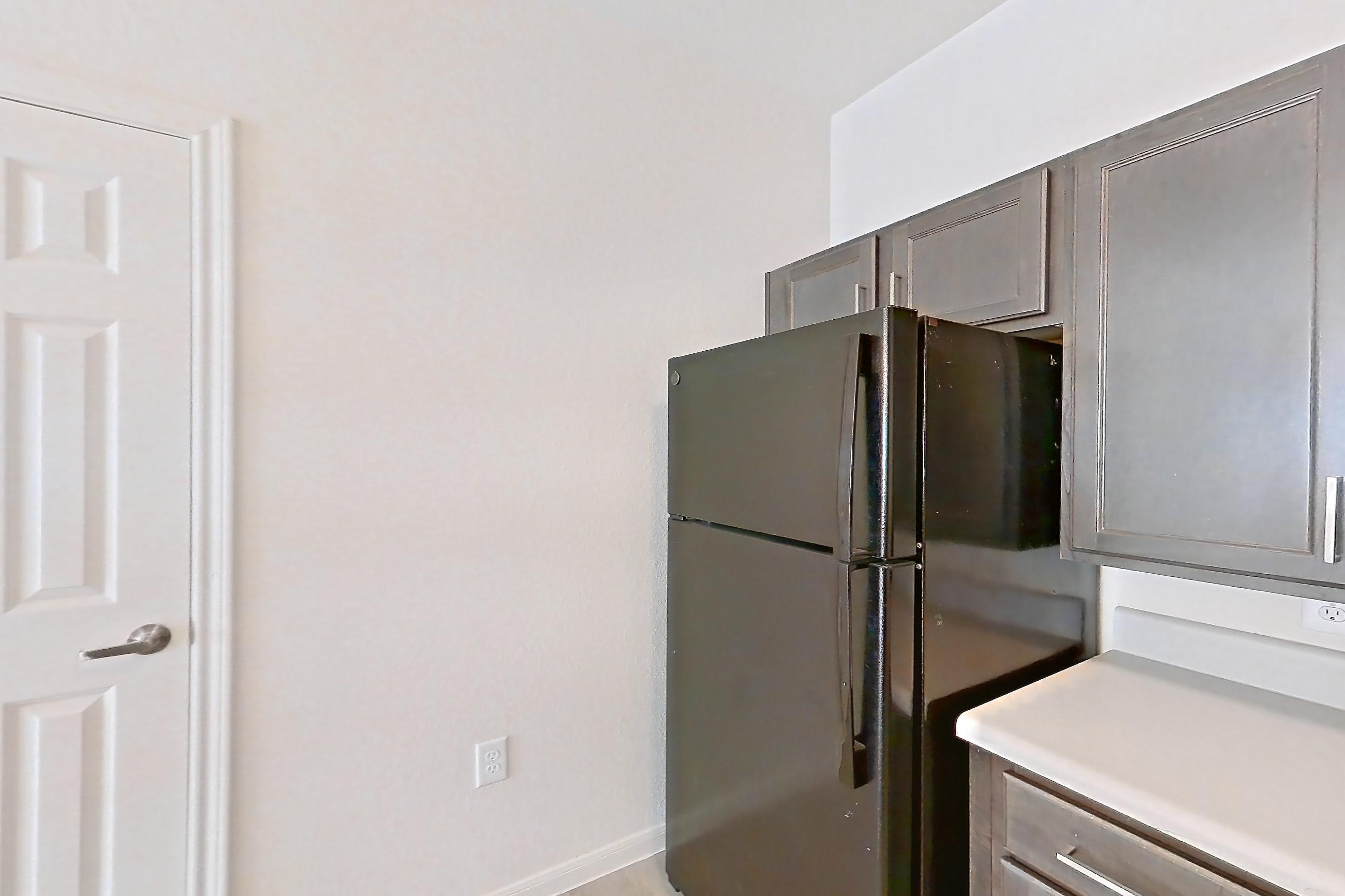 Kitchen with black appliances, light countertops, light wood-finish flooring, microwave, oven/range, and refrigerator, Apartment 10101 at Crosswinds