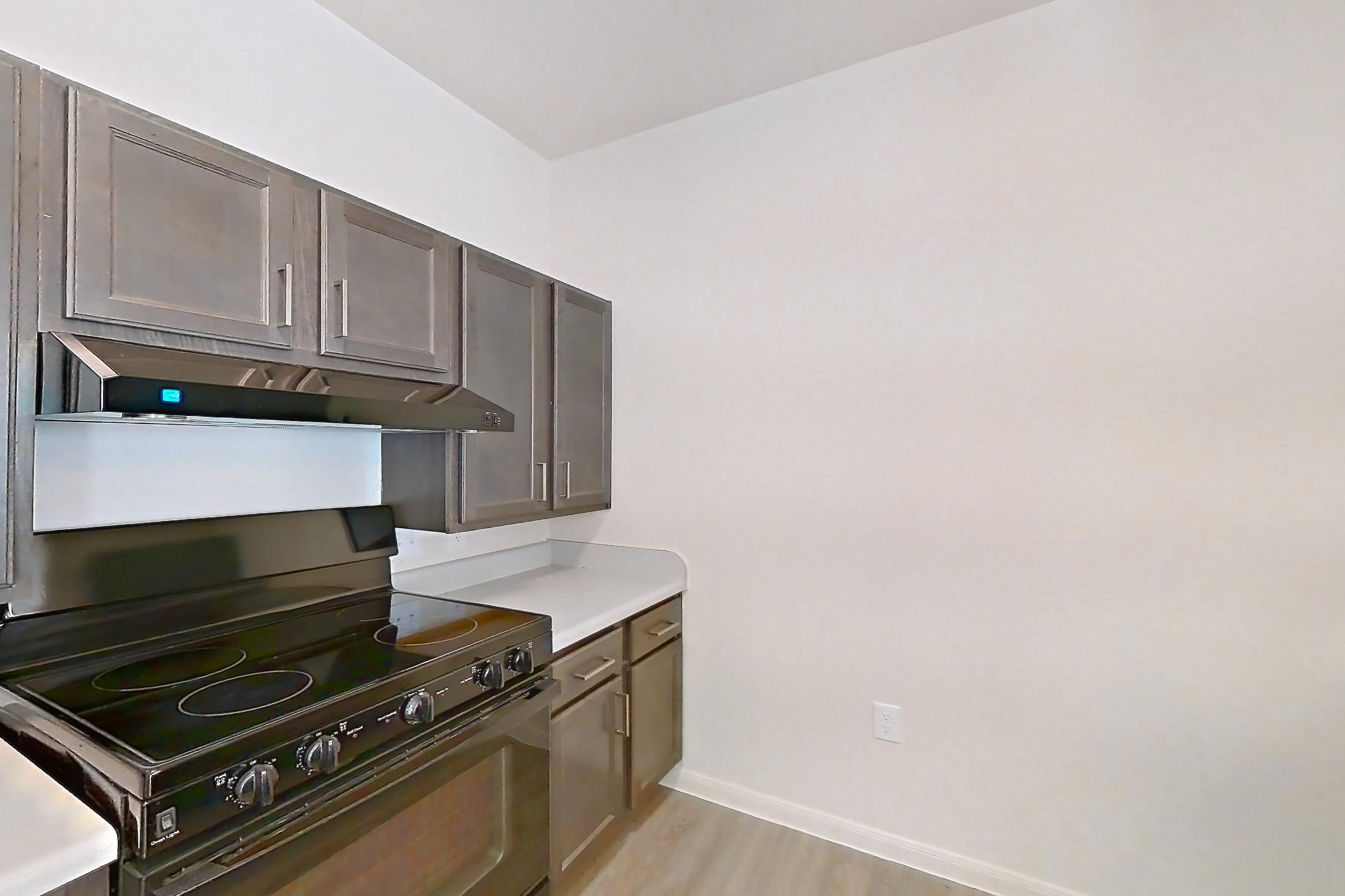 Kitchen with black appliances, light countertops, light wood-finish flooring, microwave, oven/range, and refrigerator, Apartment 10101 at Crosswinds