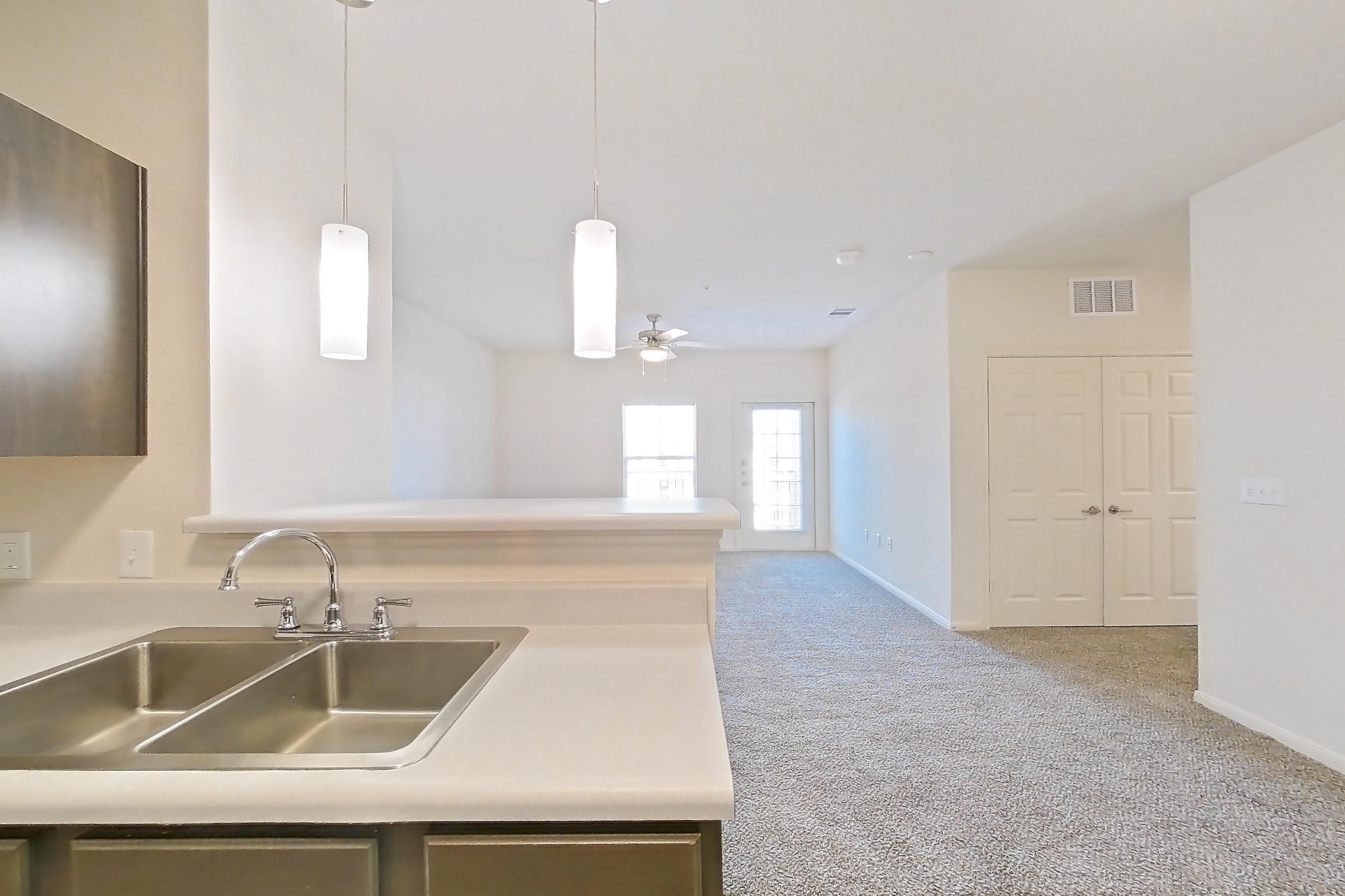 Kitchen with black appliances, dishwasher, electric range, light countertops, light wood-finish flooring, oven/range, refrigerator, and stainless steel appliances, Apartment 11203 at Crosswinds