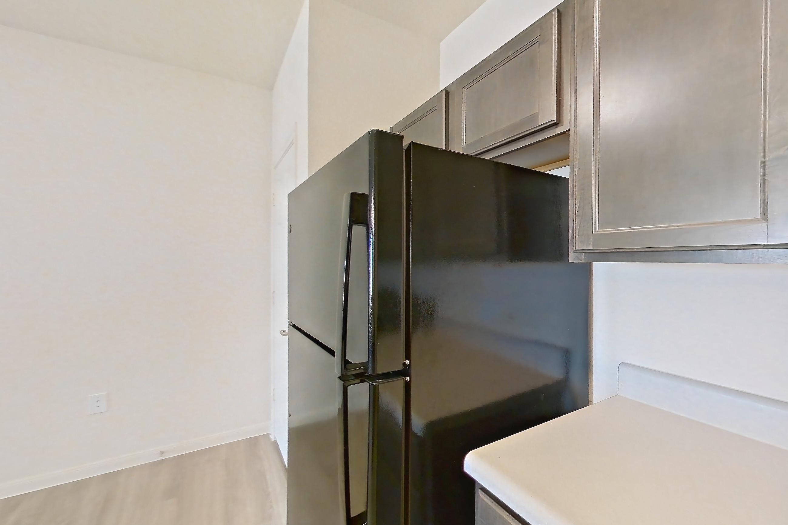 Kitchen with black appliances, dishwasher, electric range, light countertops, light wood-finish flooring, oven/range, refrigerator, and stainless steel appliances, Apartment 11203 at Crosswinds