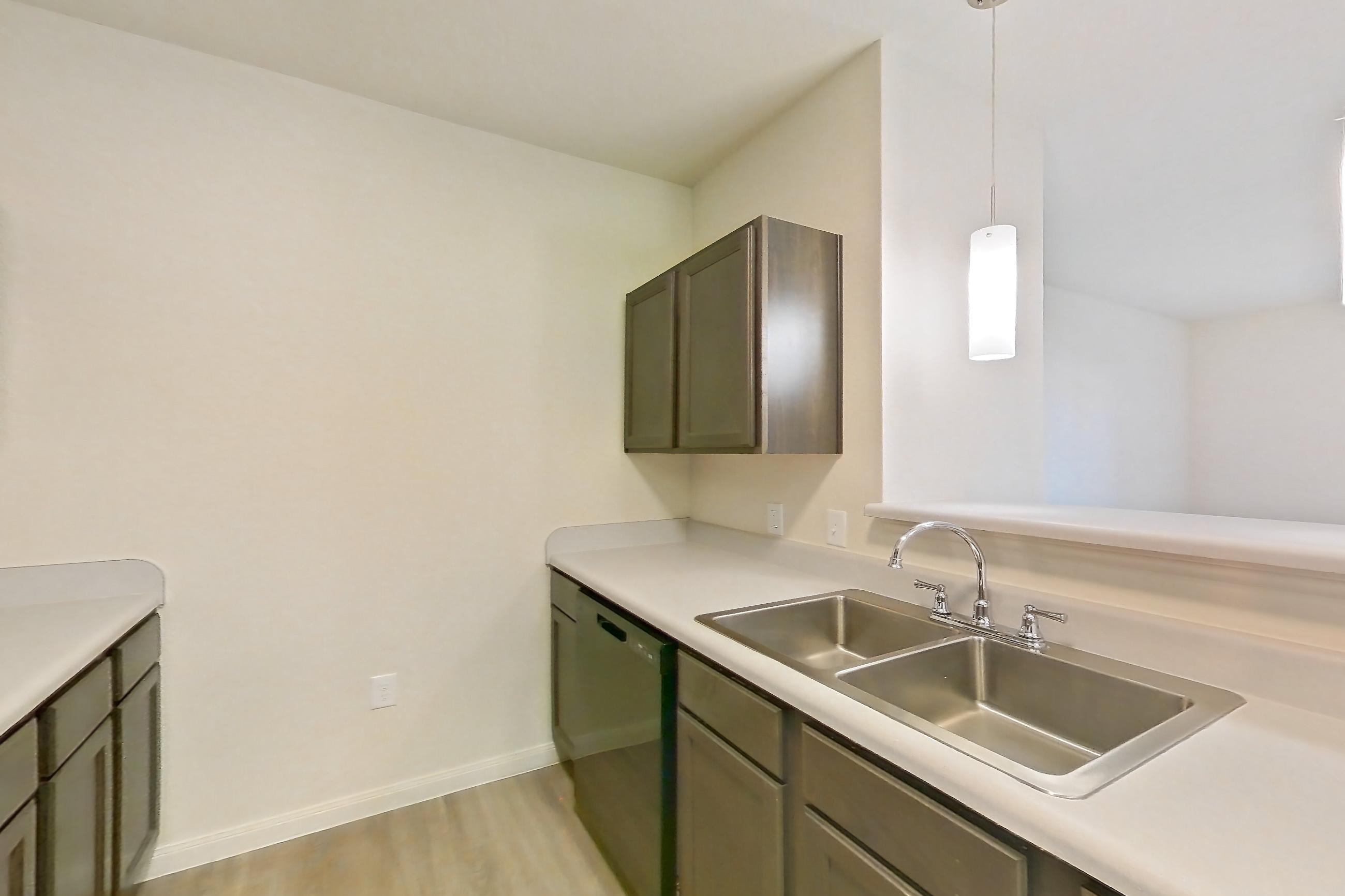 Kitchen with black appliances, dishwasher, electric range, light countertops, light wood-finish flooring, oven/range, refrigerator, and stainless steel appliances, Apartment 11203 at Crosswinds
