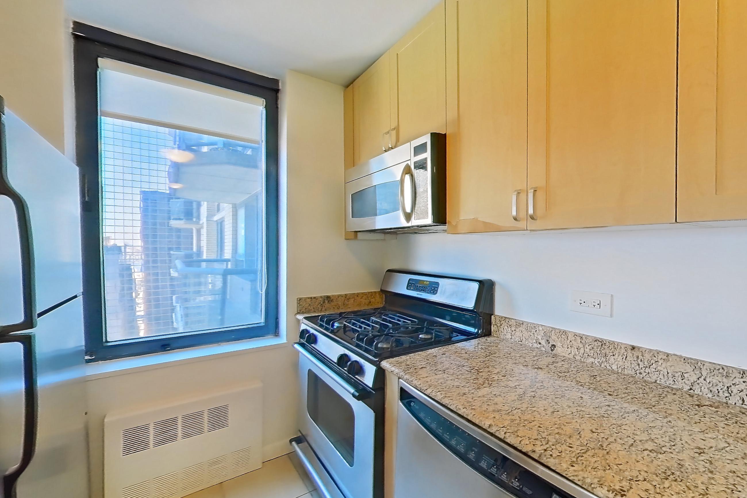 Kitchen with dishwasher, gas range, light stone countertops, light tile flooring, microwave, oven/range, refrigerator, and stainless steel appliances, Apartment 36M at Stonehenge Leasing
