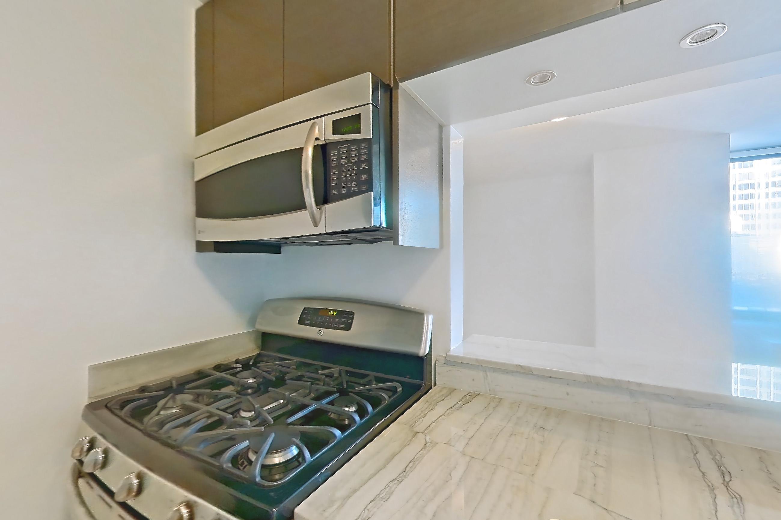 Kitchen with dishwasher, gas range, light countertops, light stone countertops, light tile flooring, light wood-finish flooring, microwave, oven/range, refrigerator, and stainless steel appliances, Apartment 28A at Stonehenge Leasing