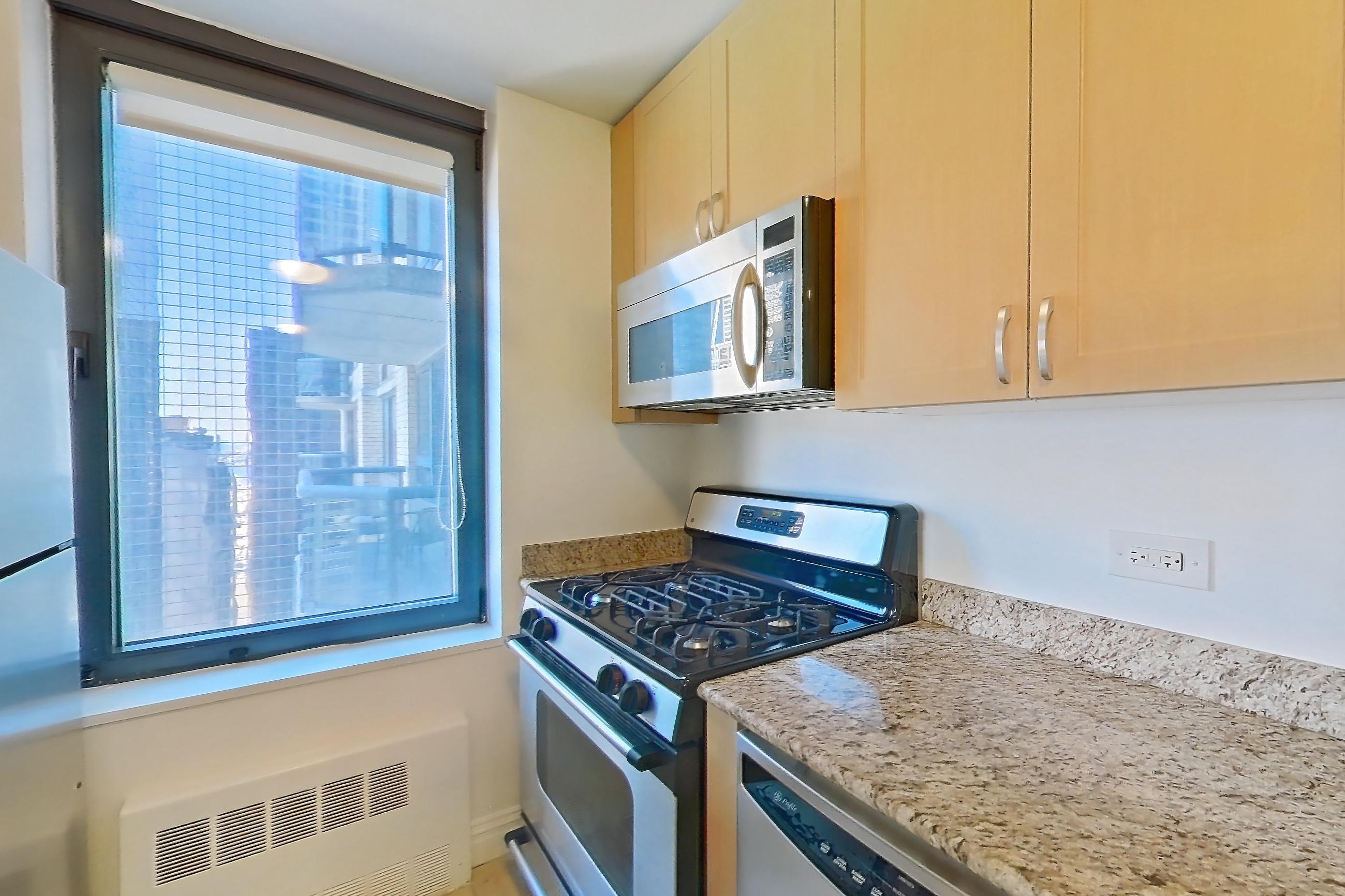 Kitchen with dishwasher, gas range, light countertops, light stone countertops, light tile flooring, microwave, oven/range, refrigerator, and stainless steel appliances, Apartment 35M at Stonehenge Leasing