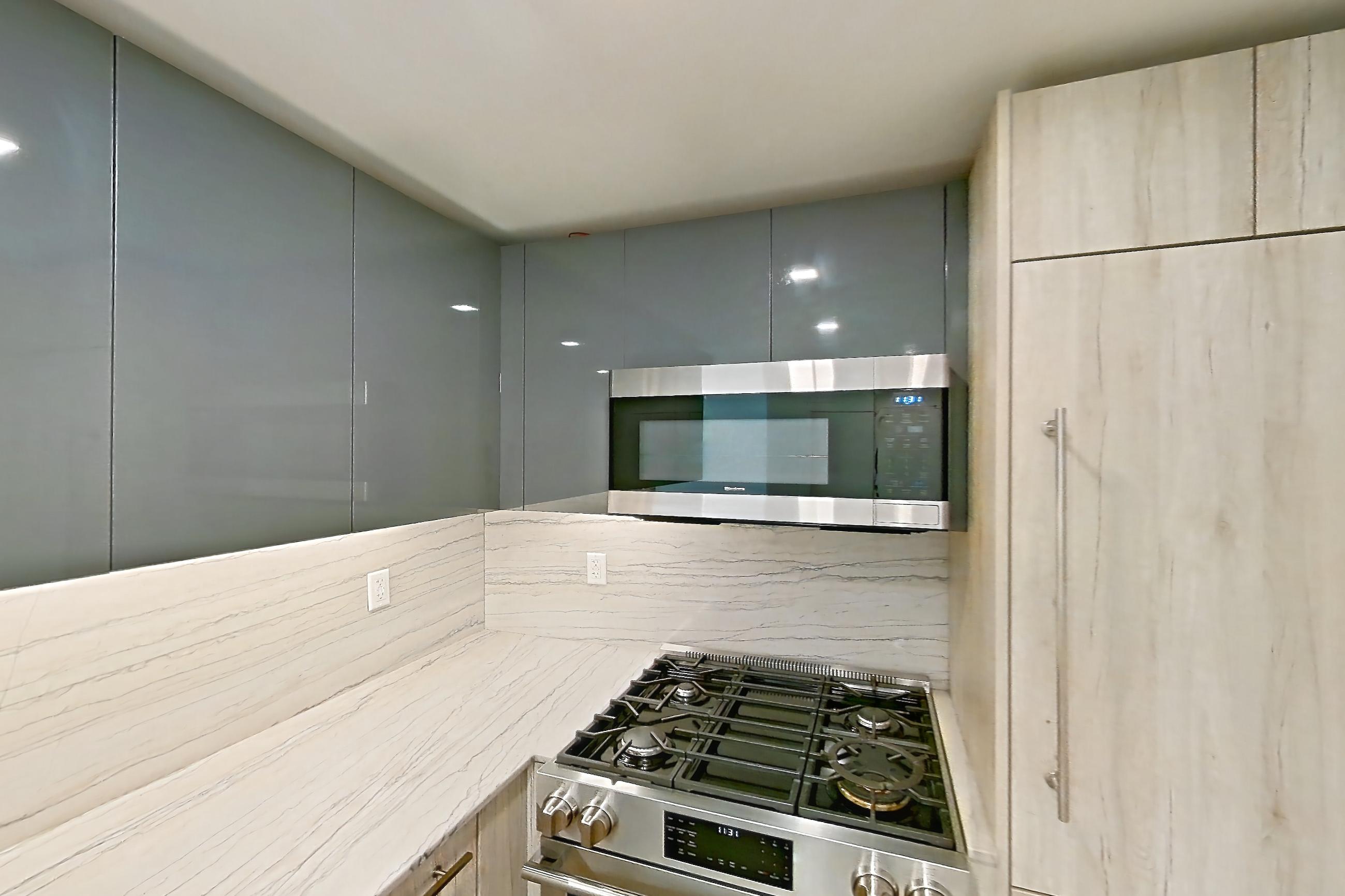 Kitchen with gas range, light countertops, light stone countertops, microwave, oven/range, and stainless steel appliances, Apartment 14D at Stonehenge Leasing