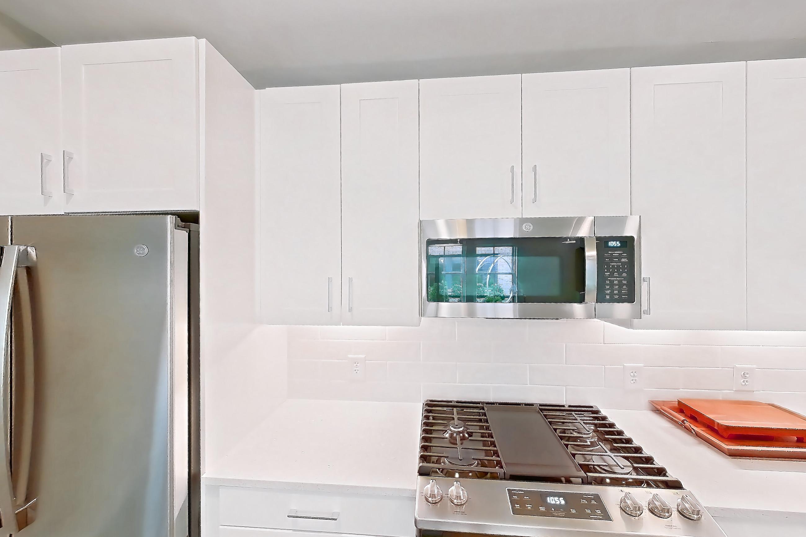 Kitchen with gas range, light countertops, light stone countertops, light wood-finish flooring, microwave, oven/range, refrigerator, and stainless steel appliances, Apartment Test at Peek Content Partner Demo