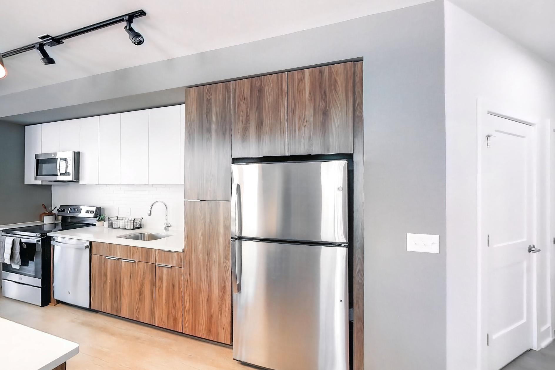Kitchen with dishwasher, electric range, light stone countertops, light wood-finish flooring, oven/range, refrigerator, and stainless steel appliances, Apartment L3 Model at Rye House