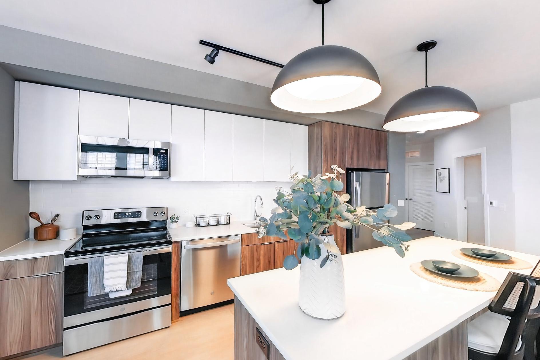 Living space with dishwasher, electric range, light stone countertops, light wood-finish flooring, microwave, oven/range, and stainless steel appliances, Apartment L3 Model at Rye House