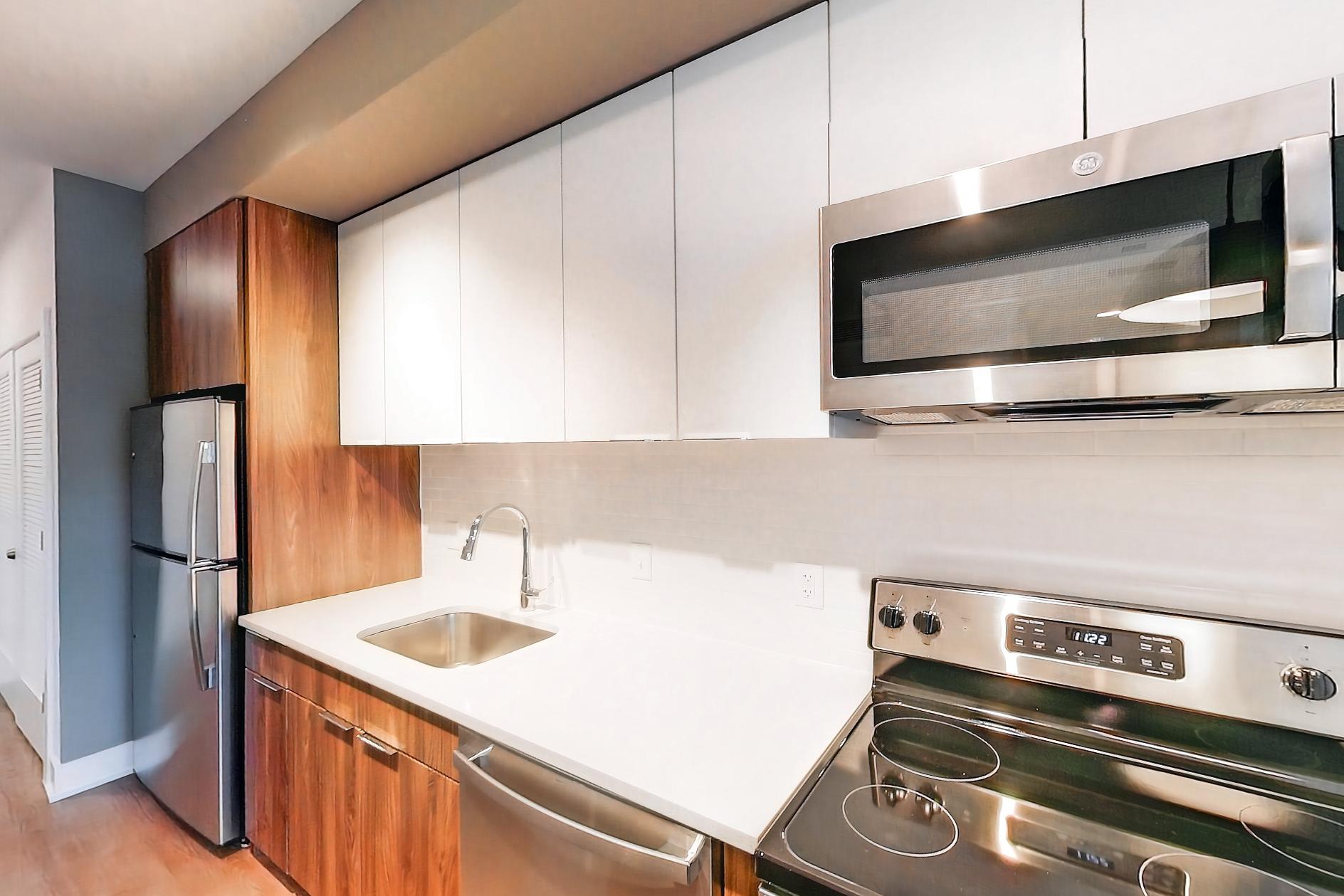 Kitchen with dishwasher, electric range, light countertops, light stone countertops, microwave, oven/range, and stainless steel appliances, Apartment L2 Model at Rye House