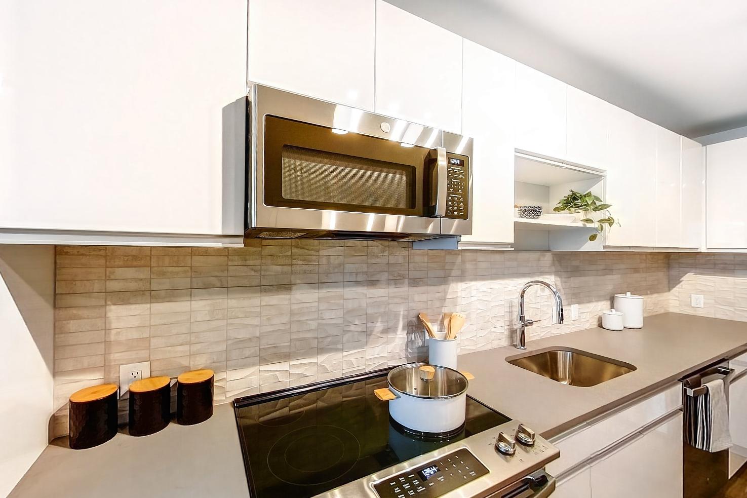 Dining room with electric range, light countertops, light stone countertops, light wood-finish flooring, microwave, oven/range, and stainless steel appliances, Apartment Model at 250 Mission