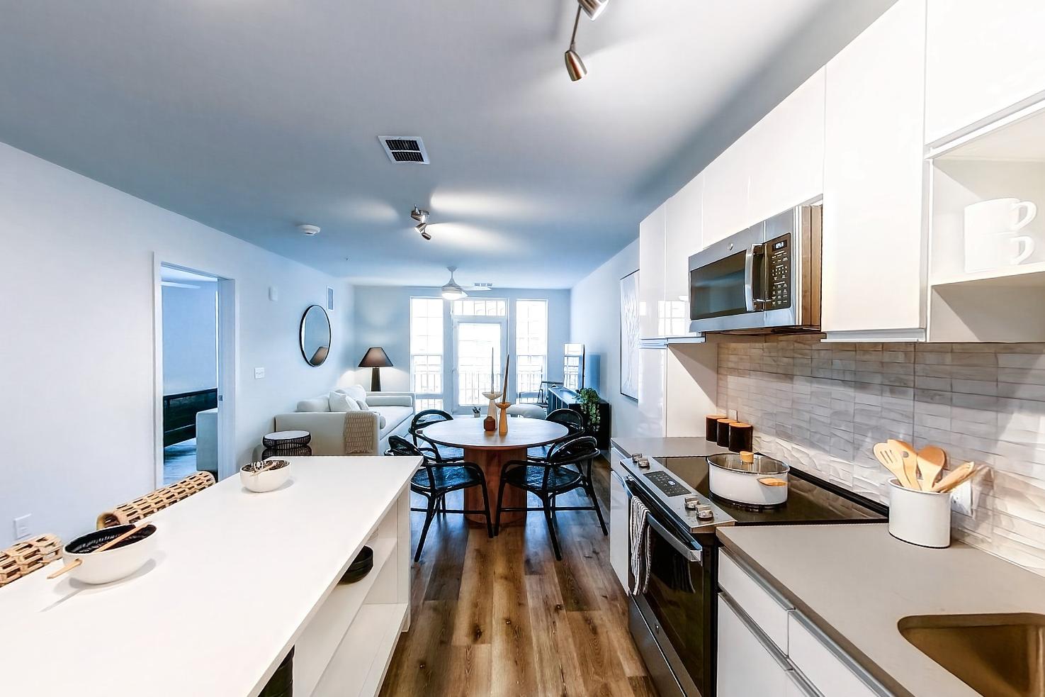 Kitchen with dishwasher, electric range, light countertops, light stone countertops, light wood-finish flooring, microwave, oven/range, and stainless steel appliances, Apartment Model at 250 Mission